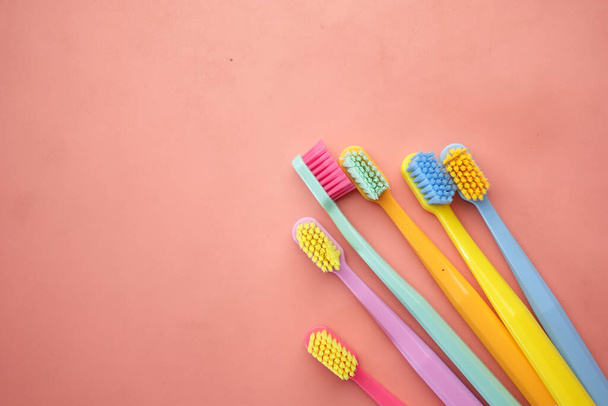  colorful toothbrushes on pink background top view , - Foto, Bild