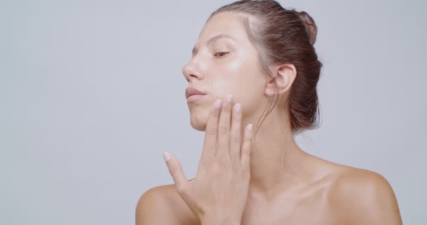 Beautiful woman massaging her face and shoulders after cream application. Clean fresh face with perfect pure skin. Skin care treatment ads concept - Footage, Video