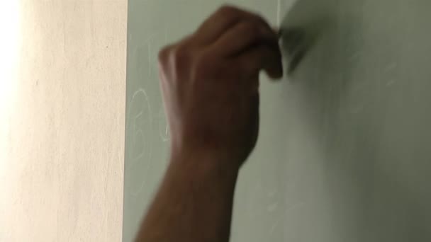Mano de un profesor varón escribiendo en pizarra verde durante una clase de educación para presos en una cárcel argentina. Primer plano.   - Imágenes, Vídeo