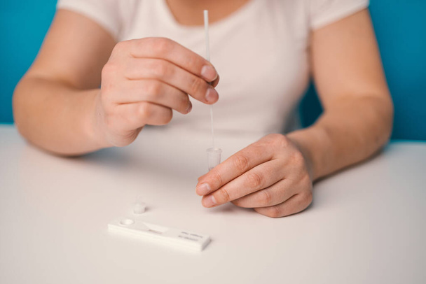 Woman hands using rapid antigen test kit for self test COVID-19 epidemic at home. Adult female unpacking a swab for inserts into her nose. COVID-19 coronavirus pandemic protection concept.  - Photo, image