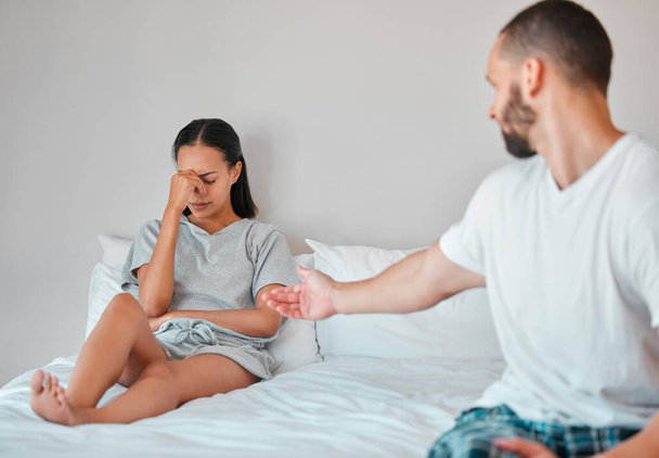 Comfort, crying and sad couple in bed after fight, argument and disagreement at home. Love, marriage and young man reaching to console upset and depressed woman sitting in bedroom to fix relationship. - Photo, Image