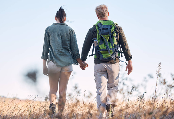 Couple, holding hands and travel or backpack adventure in bonding relationship together in the countryside. Hands of man and woman backpacking, trekking or walking in care or support for traveling. - Photo, Image