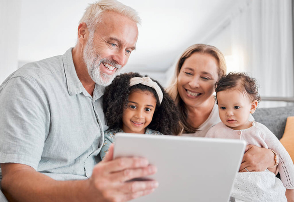Család, táblagép és online böngészés idősekkel, akik unokákra vigyáznak a családi házban. Nagyapa, nagymama és unokák digitális táblagéppel az internetes média közvetítéséhez. - Fotó, kép