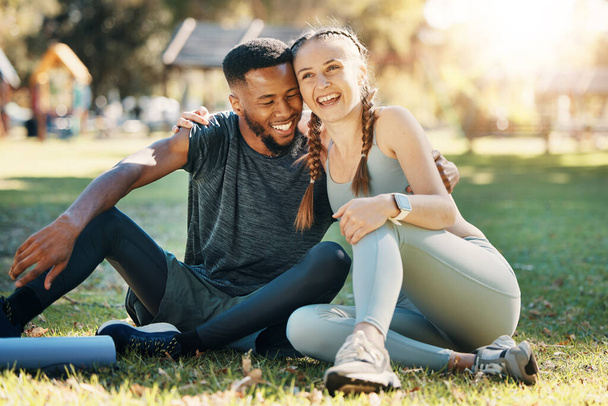 Couple, fitness and sitting on grass, park or lawn together in sunshine for fitness, wellness and health. Interracial relationship diversity or black man with woman, relax or rest at outdoor training. - Photo, Image