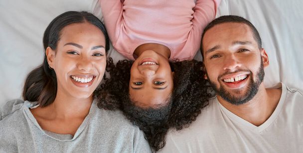 Love, bed and portrait of black family relax at home for peace, bonding and enjoy morning quality time together. Bedroom, smile and happy family face of African mother, father and kid girl top view. - Photo, Image
