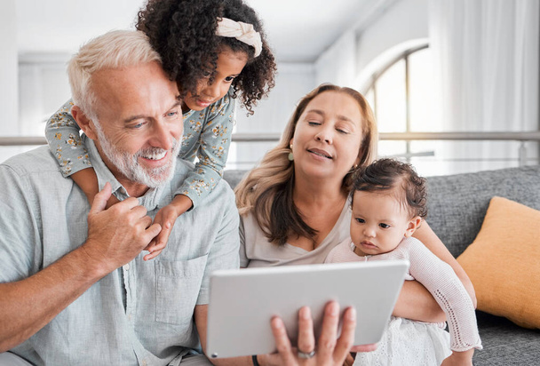 Relax, tablet and grandparents with children on sofa for movie, cartoon or educational app online. Grandmother, grandpa and kids streaming entertainment in interracial family home in Mexico - Photo, image