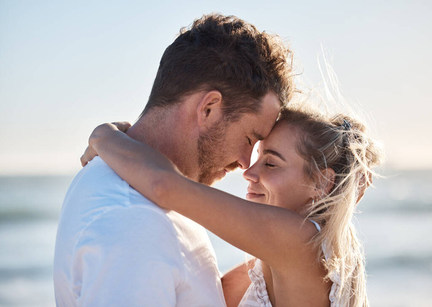 Couple, love and hug on beach eyes closed, smile and happy for relax travel vacation or quality time together. Happiness, man and woman hugging for romance marriage, honeymoon or holiday in sunshine. - Фото, зображення