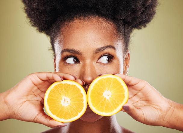 Black woman, face or thinking of orange fruit skincare, vitamin c dermatology or organic facial ideas on green studio background. Zoom, beauty model or natural hair and citrus healthy food wellness. - Фото, изображение