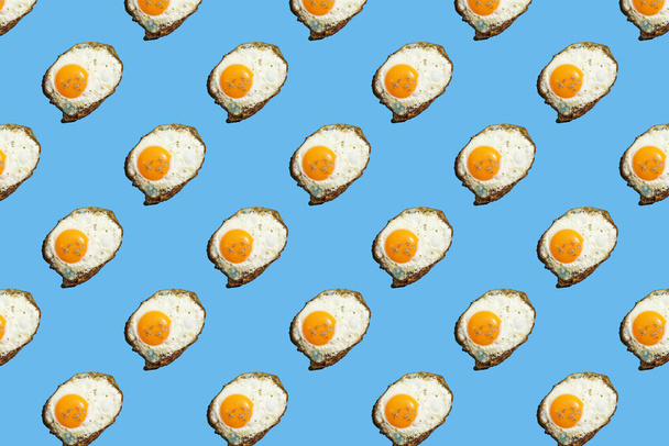 hard light pattern of a fried egg with unbroken egg yolk on a seamless blue background - Photo, Image
