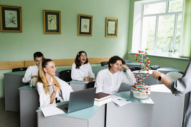 Koululaiset biologian tunnilla koulussa DNA-malli pöydällä. Biologian opettaja antaa oppitunnin oppilaille luokkahuoneessa. Koulutus koulussa biologian ja kemian - Valokuva, kuva