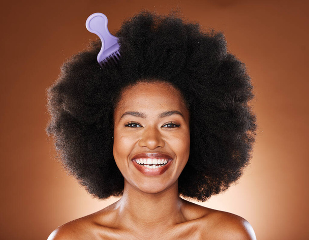 Black woman. hair care and comb in afro, happy face and skincare with smile, beauty or glow in brown studio background. Cosmetic and skin health of wellness model, happiness or content face with joy. - Foto, afbeelding