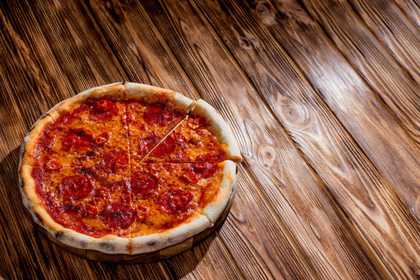 Pizza with tomato sauce, mozzarella, salami, chili, honey on wood background. View from above, copy space. - Foto, Imagem