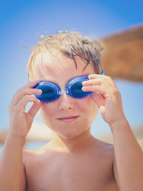 Gros plan portrait de mignon garçon caucasien portant des lunettes de natation bleues tout en profitant week-end en plein air - Photo, image
