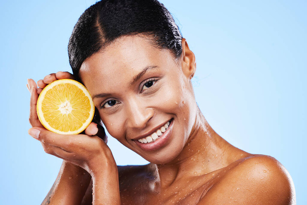 Skincare, beauty and orange fruit for black woman in studio for cosmetics, vitamin c and dermatology benefits with water drops on skin. Portrait, face and smile of model with natural product for skin. - Foto, imagen