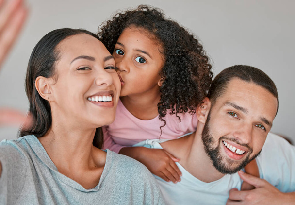 Family, portrait and selfie with child, mother and father together at home for kiss, love and care with smile and happiness. Child, man and woman in Puerto Rico house for social media profile picture. - Фото, изображение