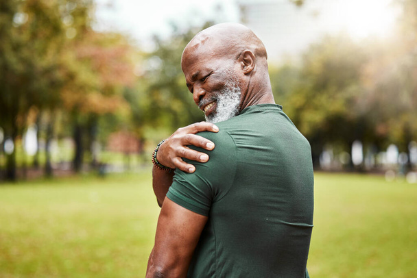 Senior zwarte man met schouderpijn, fitness blessure en lichaamsbeweging in het park met spierpijn of ontsteking buiten. Gezondheid, ongeval tijdens de training en pijn, bejaarde met pijn uit de sport - Foto, afbeelding