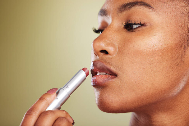Lipstick, black woman and skincare for wellness, cosmetics, smooth lips or against brown studio background. Makeup, African American female or girl with lip balm, for gloss or soft for natural beauty. - Photo, Image