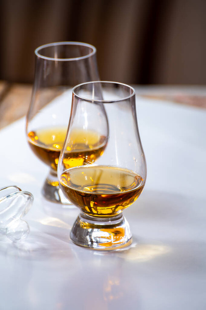 Verkostung von Whisky, Tulpenförmigen Probiergläsern mit einem Schuss Scotch Single Malt oder Blended Whisky auf weißem Tisch, Nahaufnahme - Foto, Bild