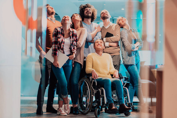 Businesswoman in a wheelchair on break in a modern office with her team in the background. High quality photo - Photo, Image