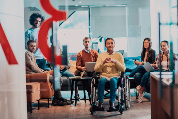 A businesswoman in a wheelchair having a business meeting with the team at a modern office. A group of young freelancers agree on new online business projects.  - Foto, Imagem