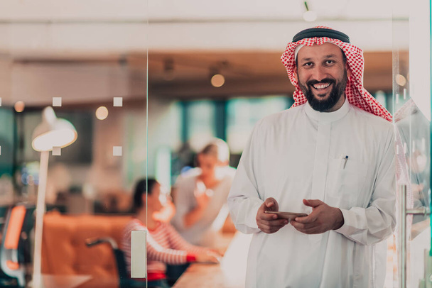 Середньосхідний арабський бізнесмен в офісі говорить на смартфоні перед своєю командою. Фотографія високої якості - Фото, зображення