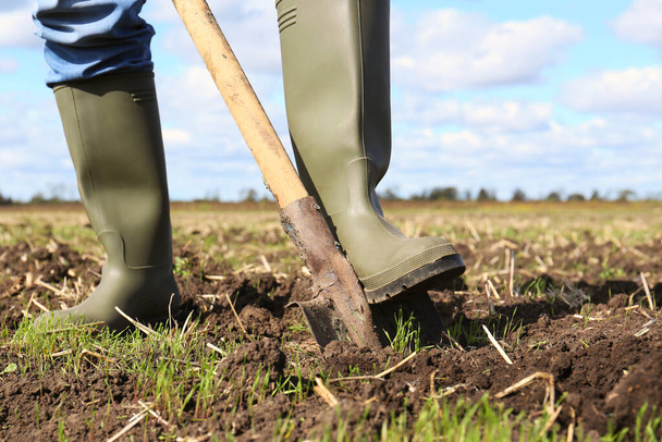 Man digging soil with shovel in field, closeup - Фото, изображение