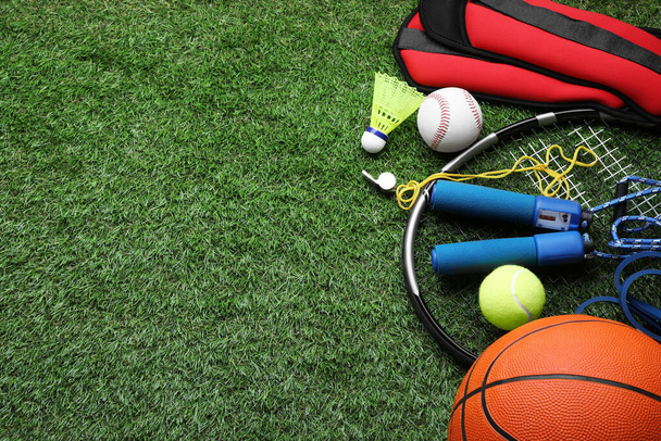 Set of different colorful sports equipment on green grass, above view. Space for text - Фото, изображение
