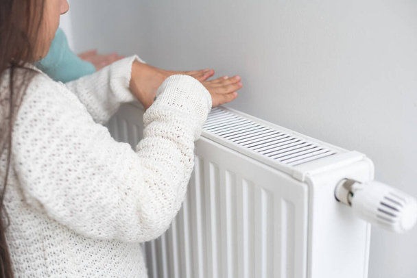 Fille chaude mains près du radiateur à la maison - Photo, image