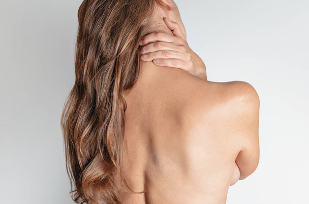 nackte Frau mit Schmerzen im Nacken und Rücken auf weißem Hintergrund. zurück. - Foto, Bild