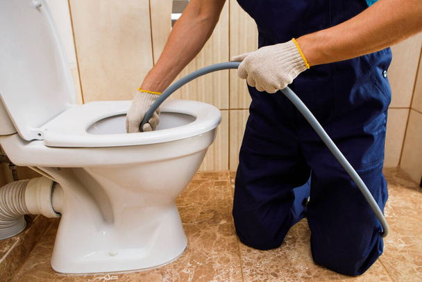 plumber unclogging blocked toilet with hydro jetting at home bathroom. sewer cleaning service - Foto, imagen