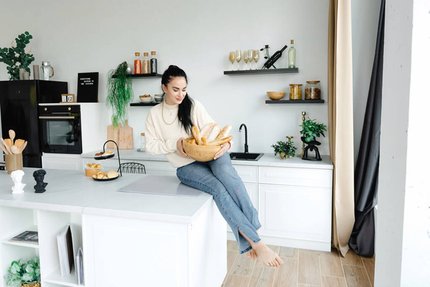 Las mujeres en la cocina moderna celebran el aprendizaje alegre. Panadería casera de negocios en casa. Una chica sosteniendo una cesta de sus productos. - Foto, imagen