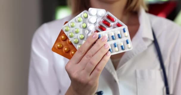 El médico cardiólogo terapeuta o neurólogo sostiene un paquete de varias ampollas de píldoras. Panacea medicamentos recetados y farmacia - Metraje, vídeo
