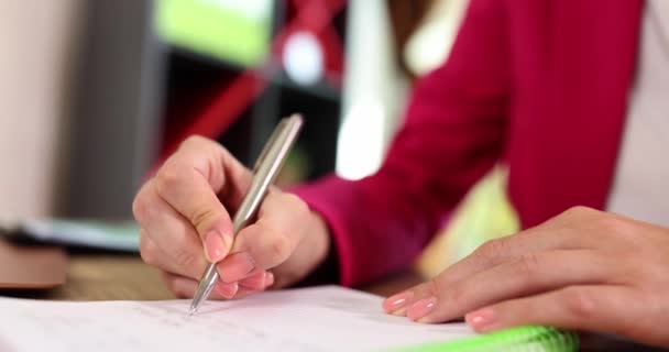Closeup of businesswoman hands holding pen, makes notes in notebook and performs test task. Woman entrepreneur writes down important data information and creative startup ideas concept - Footage, Video