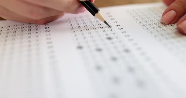 Persoon lost testen op en schrijft met potlood op papier. Meerkeuzeexamen of student testen - Video
