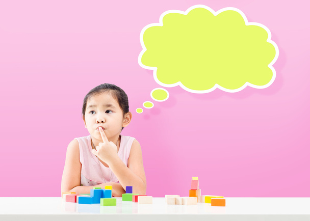 Thinking little girl with empty bubble and wooden building blocks on table - Photo, Image