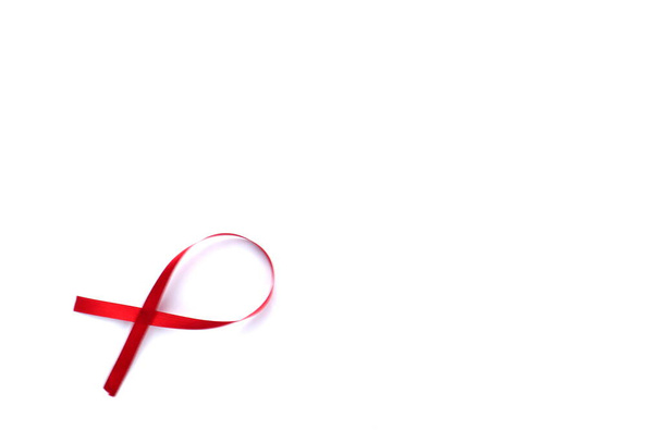 Červená páska podpory izolované na bílém pozadí. Světový den pomoci a národní měsíc povědomí o HIV / AIDS a stárnutí červenou stuhou. copyspace area - Fotografie, Obrázek