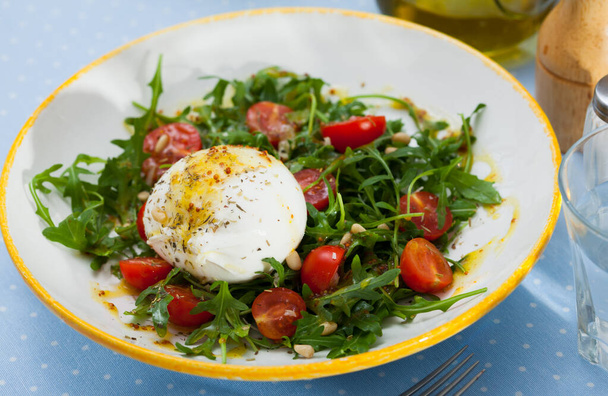 Close up of salad with burrata cheese, pine nuts, cherry tomatoes and arugula with spice at plate - Φωτογραφία, εικόνα