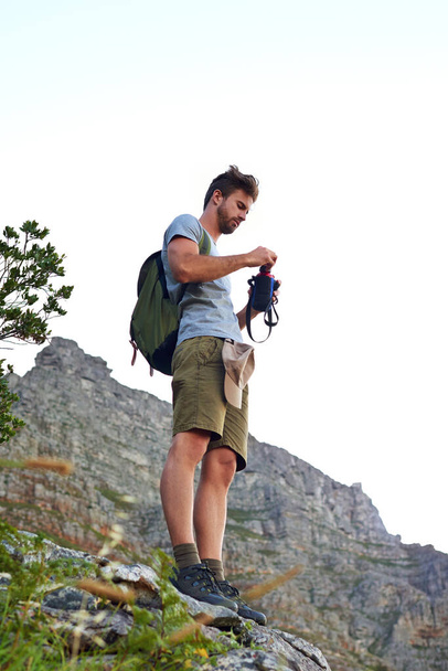 Staying hydrated. a handsome young man opening a bottle of water while hiking - Foto, Imagen