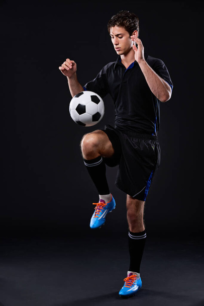 Do it with passion or not at all. Full length studio shot of a handsome young soccer player isolated on black - Foto, Bild