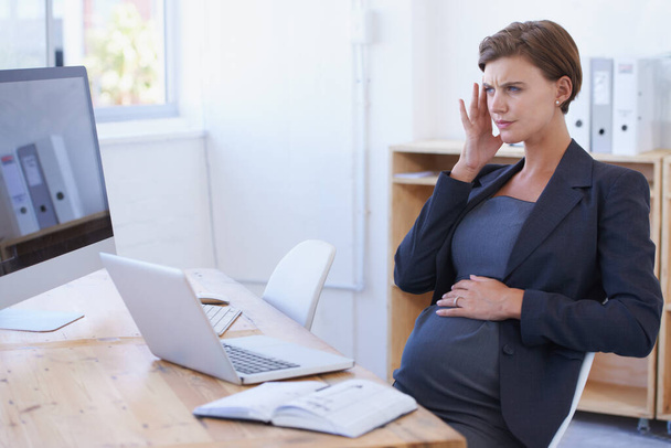 Η εγκυμοσύνη έχει ως αποτέλεσμα πολλά συμπτώματα. Μια έγκυος επιχειρηματίας που κάνει μασάζ στον κρόταφο για να ανακουφίσει τον πονοκέφαλο. - Φωτογραφία, εικόνα