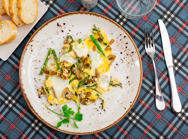 Traditional Spanish breakfast is a Revuelto, which is an omelet with chicken and mushrooms with asparagus. Decorated with a ..sprig of fresh greenery - Φωτογραφία, εικόνα