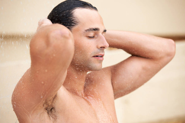 Почувствуй свежесть. красивый молодой человек наслаждается освежающим душем - Фото, изображение
