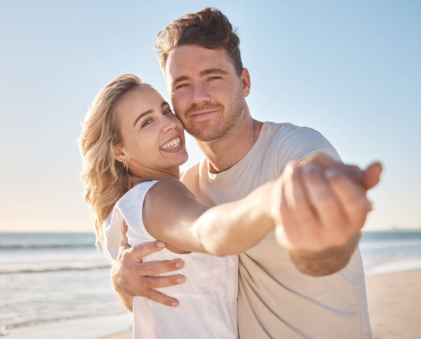 Couple, portrait smile and hug for love, care or support in summer vacation bonding together at the beach. Happy man and woman holding hands smiling for relationship holiday break by the ocean coast. - 写真・画像