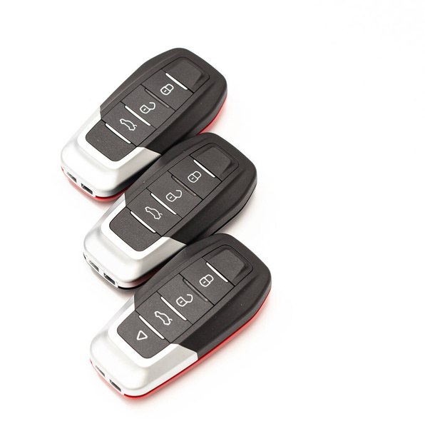 Car keys lie in different poses on a white background. Black and red car alarm key fobs are located on a white background. - 写真・画像