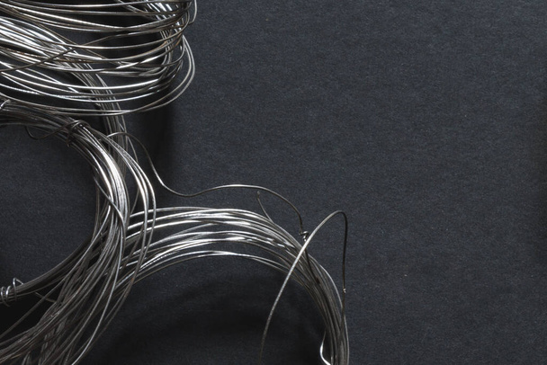 coils of thin steel wire on a dark background - Foto, imagen