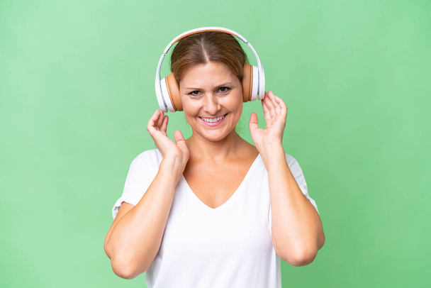 Middle-aged caucasian woman over isolated background listening music - Foto, Bild