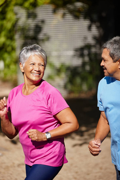 Enjoying a fun run. a mature couple jogging together on a sunny day - Photo, Image