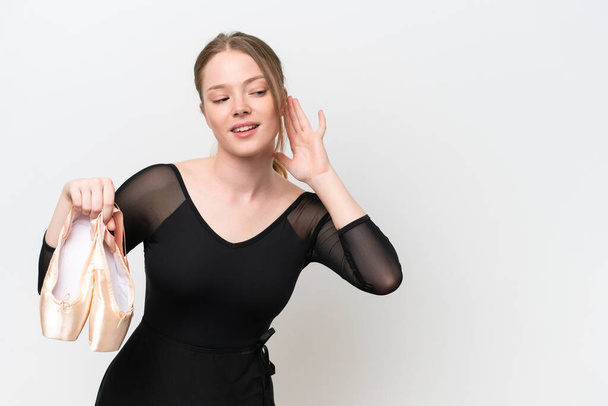 Young woman practicing ballet isolated on white background listening to something by putting hand on the ear - Fotografie, Obrázek