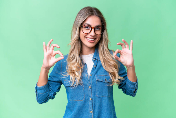 Young Uruguayan woman over isolated background showing ok sign with two hands - Photo, Image