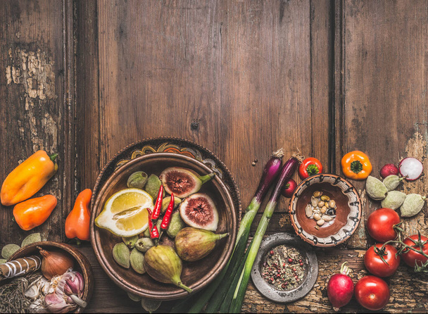 Healthy food and snack background. Bowls with tasty ingredients of Mediterranean cuisine: various vegetables, olives, pickled pepperoni and figs on wooden rustic table. Top view. Place for text - Zdjęcie, obraz
